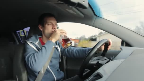 A részeg sofőr alkoholt iszik üvegből a járműben. Törvénysértés, autóvezetés, bűnözés. Ivás kormányzás közben — Stock videók