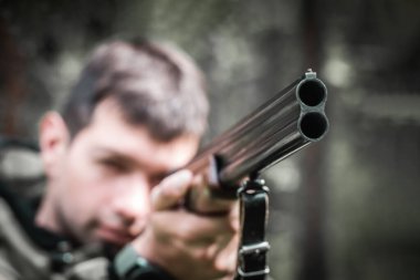 Hedefe yakın mesafeden namlulu namlulu silah taşıyan bir adam. Ön manzara. Tehlike ve suç kavramı. Avcının elinde av tüfeği