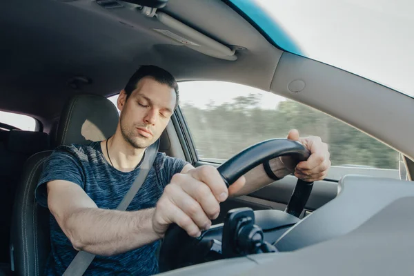 Fáradtság alvó vezető vezetés sebességgel, miközben tartja a kereket vezetés közben autópályán az erdőben. A kimerült ember elölnézete — Stock Fotó