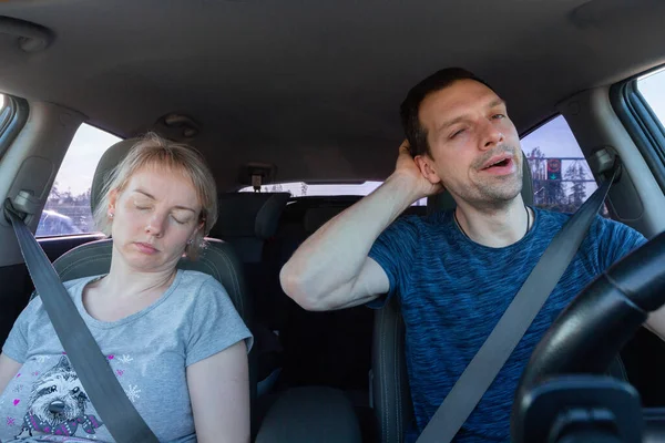 Fáradt ásítozó férfi autót vezet és alvó nő együtt utazás közben. Biztonsági övet viselő utasok és járművezető — Stock Fotó