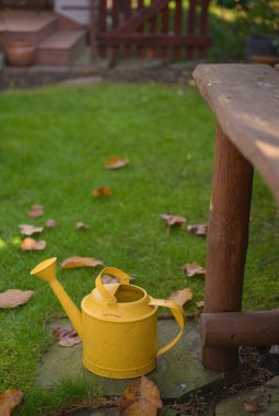 Bahçe çardağındaki masada sarı metal bir sulama kutusu var.