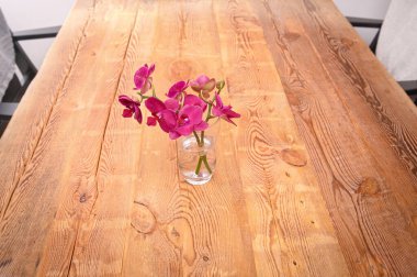 Eski çam ağacından yapılmış bir masada orkide çiçekleri. 