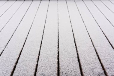 Balkondaki döşeme tahtaları karla kaplı.