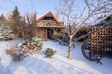 Teraslı, balkonlu ve karla kaplı bahçeli geleneksel bir ev.