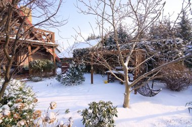 Teraslı, balkonlu ve karla kaplı bahçeli geleneksel bir ev.