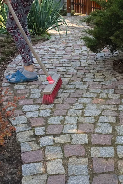 Sweeping a granite paving path in the spring garden