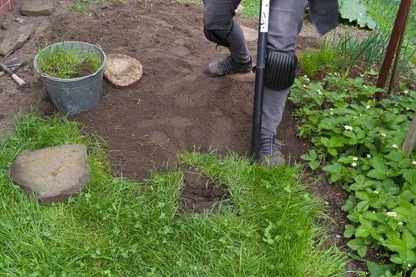 シャベルを使って庭の草を掘る人 — ストック写真