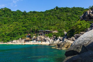 Koh Tao, Tayland 22 Nisan 2019 Mango Körfezi manzaralı, plajda ahşap tatil köyü, kristal mavi sularda tekne.