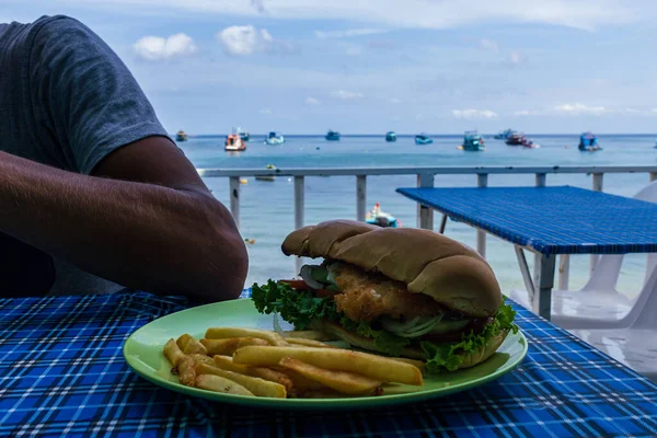 Thailand island sea restaurant, fast food chicken burger with free on green plate. blue table outdoor furniture