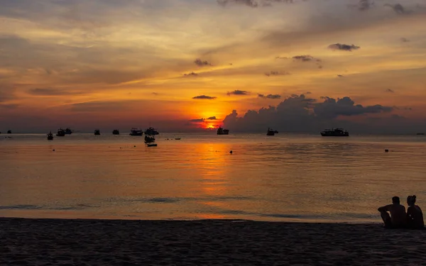 Koh Tao, Tayland: 23 Nisan 2019: Ada köyü tekne iskelesi, plajda akşam vakti, beyaz kumsalda oturan çift manzaranın keyfini çıkarın