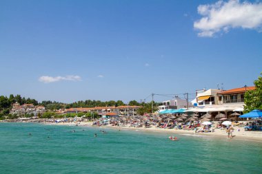 Siviri, Yunanistan, 10 Temmuz 2021. Yunanistan, Yunan bayrağıyla Siviri plajı manzarası. Eski balıkçı limanı Kassandria, bugün inanılmaz kumlu bir plajı olan küçük, güzel bir turistik köy.