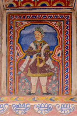 Mandawa, Hindistan, 21 Ekim 2025. Mandawa 'da elinde çiçek tutan bir savaşçıyı betimleyen haveli bir duvar resmi.