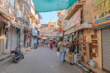 Jaisalmer, Hindistan, 24 Ekim 2025. Jaisalmer 'de dar bir sokak, güneşten korunmak için yeşil tentelerle kaplanmış ve gölgelenmiş..