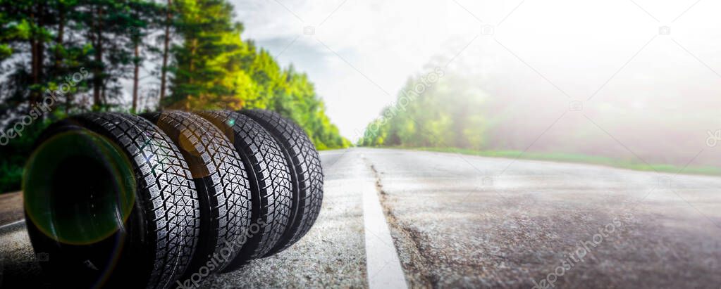 All car tire on summer forest road with blur trees in background. Change for winter tire.Wider banner