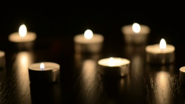 Muitas pequenas velas flamejantes na mesa preta — Vídeo de Stock