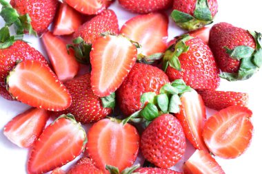 Beyaz tabak arka planında izole edilmiş çilekler, taze dilimler, parçalar, yarım çilek meyvesi.