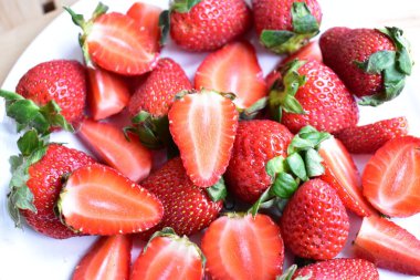 Beyaz tabak arka planında izole edilmiş çilekler, taze dilimler, parçalar, yarım çilek meyvesi.