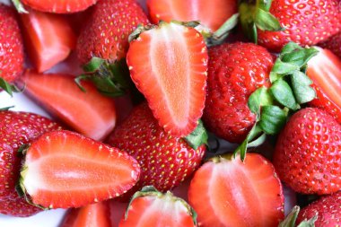 Beyaz tabak arka planında izole edilmiş çilekler, taze dilimler, parçalar, yarım çilek meyvesi.