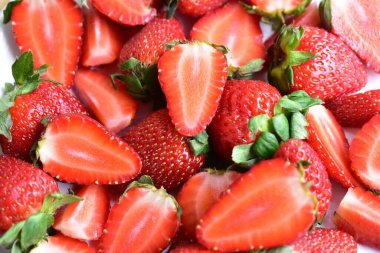 Beyaz tabak arka planında izole edilmiş çilekler, taze dilimler, parçalar, yarım çilek meyvesi.