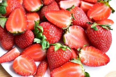 Beyaz tabak arka planında izole edilmiş çilekler, taze dilimler, parçalar, yarım çilek meyvesi.