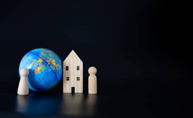 Model ahşap evler ve minyatür küreler siyah arka planda bomboş. Aynı dünyada birlikte yaşama kavramını öne sür..
