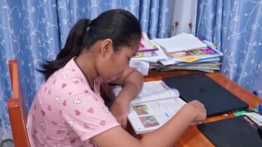 girl reading a book on a wooden table.