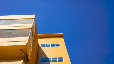 Parlak mavi gökyüzü ile sarı modern bina, geometrik tasarım ve güneş ışığı gölgesi ile minimal mimari arka plan, soyut kentsel dış konsept.