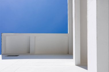 Beyaz duvar ve mavi gökyüzü ile modern minimalist mimari, temiz çizgiler, basitlik ve çağdaş yapı tasarımı kavramını gösteren soyut geometrik perspektif.