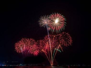 Kutlama gecesinde inanılmaz güzel renkli havai fişek gösterisi, deniz sahilinde su üzerinde çok renkli yansımalarla gösteriliyor. 