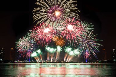 Kutlama gecesinde inanılmaz güzel renkli havai fişek gösterisi, deniz sahilinde su üzerinde çok renkli yansımalarla gösteriliyor. 