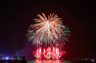 Kutlama gecesinde inanılmaz güzel renkli havai fişek gösterisi, deniz sahilinde su üzerinde çok renkli yansımalarla gösteriliyor.  