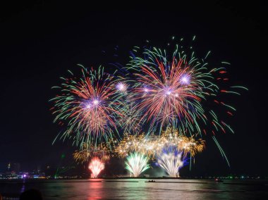 Kutlama gecesinde inanılmaz güzel renkli havai fişek gösterisi, deniz sahilinde su üzerinde çok renkli yansımalarla gösteriliyor.  