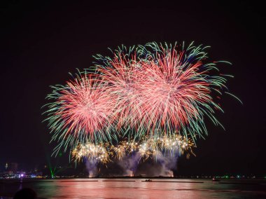 Kutlama gecesinde inanılmaz güzel renkli havai fişek gösterisi, deniz sahilinde su üzerinde çok renkli yansımalarla gösteriliyor.  