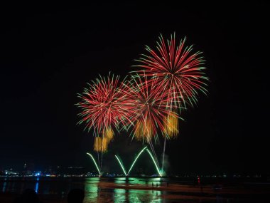 Kutlama gecesinde inanılmaz güzel renkli havai fişek gösterisi, deniz sahilinde su üzerinde çok renkli yansımalarla gösteriliyor.  