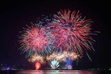 Kutlama gecesinde inanılmaz güzel renkli havai fişek gösterisi, deniz sahilinde su üzerinde çok renkli yansımalarla gösteriliyor. 