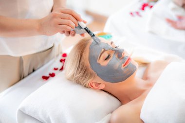 Güzel, genç, çekici, beyaz bir kadın masaj yaptırıyor ve cilt bakımı için doğal kille maske takıyor. Tayland Masörü tarafından aroma spa salonunda. Güzellik ve vücut bakımı kavramı. 