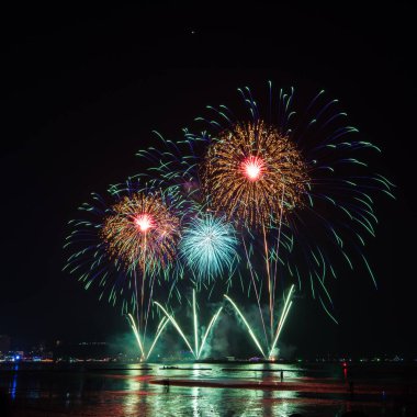 Kutlama gecesinde inanılmaz renkli havai fişek gösterisi, deniz sahilinde çok renkli yansıma ve su.