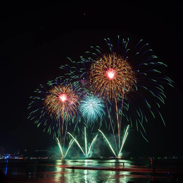 Kutlama gecesinde inanılmaz renkli havai fişek gösterisi, deniz sahilinde çok renkli yansıma ve su.