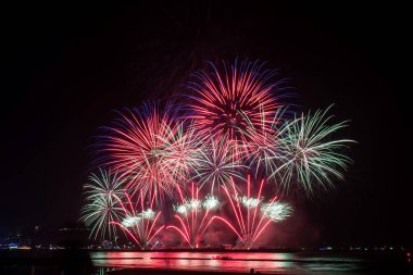 Kutlama gecesinde inanılmaz güzel renkli havai fişek gösterisi, deniz sahilinde su üzerinde çok renkli yansımalarla gösteriliyor. 