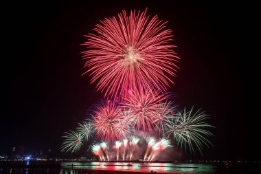 Kutlama gecesinde inanılmaz güzel renkli havai fişek gösterisi, deniz sahilinde su üzerinde çok renkli yansımalarla gösteriliyor. 