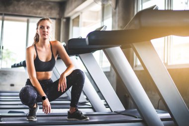 Genç çekici fitness kadınının sinematik tonu spor salonunda çalışmadan önce egzersizi ısıtır. Vücut kaslarını sağlıklı yaşam konseptine uydurmak için bireysel spor. 