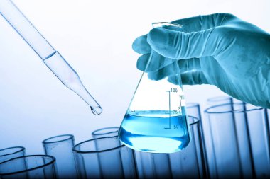 Laboratuvar geçmişi, bilim laboratuarı araştırma ve geliştirme konsepti ve laboratuvar malzemeleriyle dolu bir matarayı tutan bilim adamının eli. 