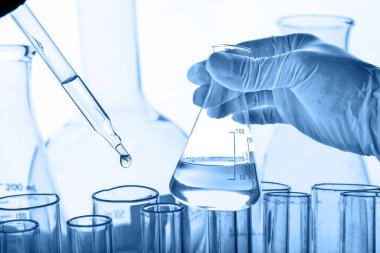 Laboratuvar geçmişi, bilim laboratuarı araştırma ve geliştirme konsepti ve laboratuvar malzemeleriyle dolu bir matarayı tutan bilim adamının eli. 