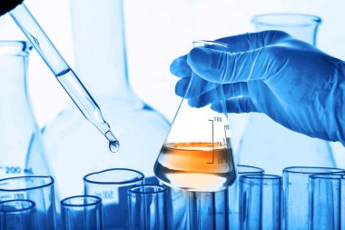 Laboratuvar geçmişi, bilim laboratuarı araştırma ve geliştirme konsepti ve laboratuvar malzemeleriyle dolu bir matarayı tutan bilim adamının eli. 