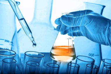 Laboratuvar geçmişi, bilim laboratuarı araştırma ve geliştirme konsepti ve laboratuvar malzemeleriyle dolu bir matarayı tutan bilim adamının eli. 