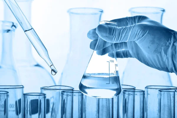 Laboratuvar geçmişi, bilim laboratuarı araştırma ve geliştirme konsepti ve laboratuvar malzemeleriyle dolu bir matarayı tutan bilim adamının eli. 