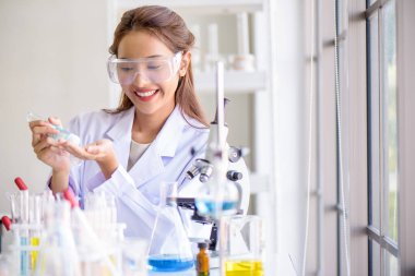 Laboratuvarda laboratuvar camlarıyla mikroskop testi yapan çekici mutluluk bilimci kadın. Bilim veya tıbbi araştırma ve geliştirme yeni antivirüs veya Covid-19 aşı konsepti. 