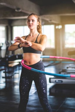 Spor salonunda egzersiz yaparken hula hoop yapan güzel, genç, çekici beyaz bir kadın. Sağlıklı spor yaşam tarzı, fitness, sağlıklı ve egzersiz konsepti. 