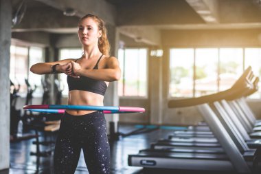 Spor salonunda egzersiz yaparken hula hoop yapan güzel, genç, çekici beyaz bir kadın. Sağlıklı spor yaşam tarzı, fitness, sağlıklı ve egzersiz konsepti. 