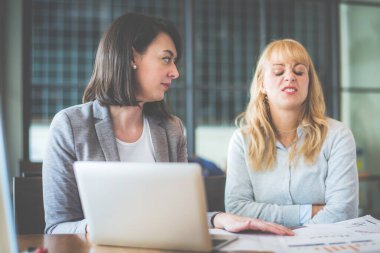 Kahve dükkanında dizüstü bilgisayar ve evrak işleriyle birlikte çalışan iki iş kadını. Renk tonu etkisi. 